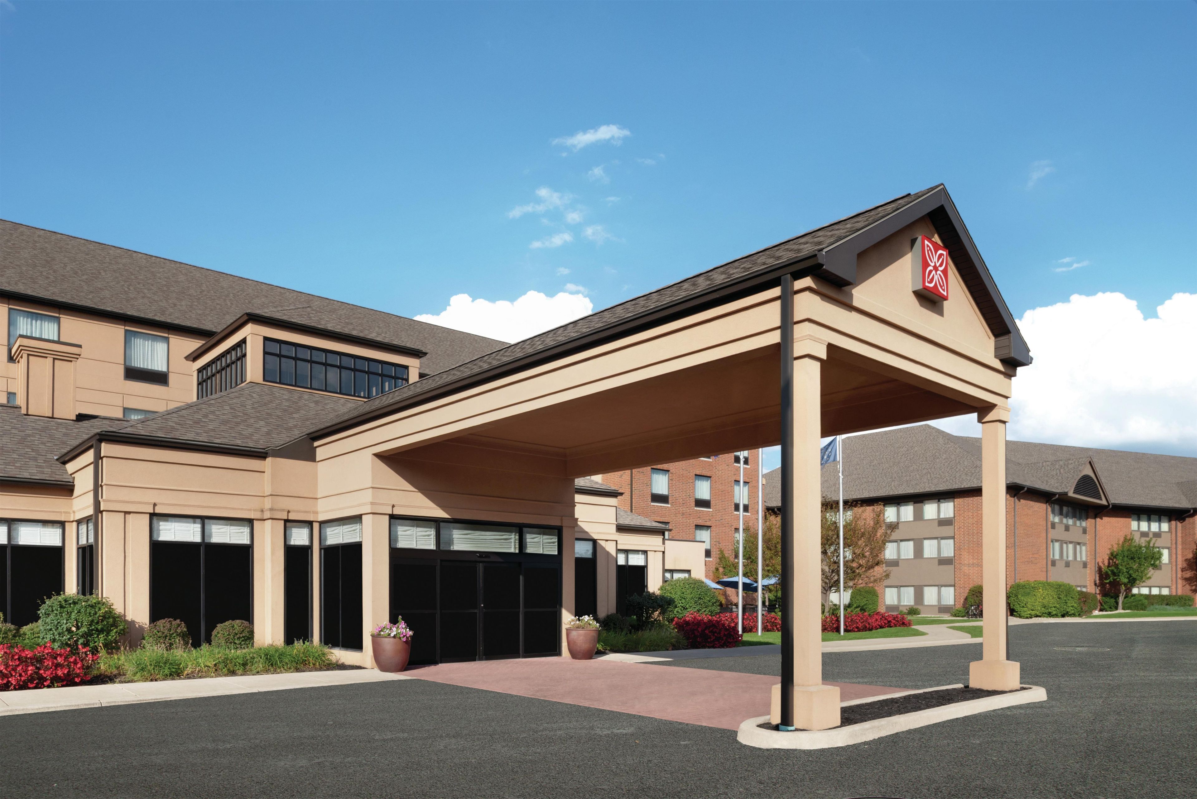 A hotel with a covered entrance, multiple windows, and a brick building in the background.