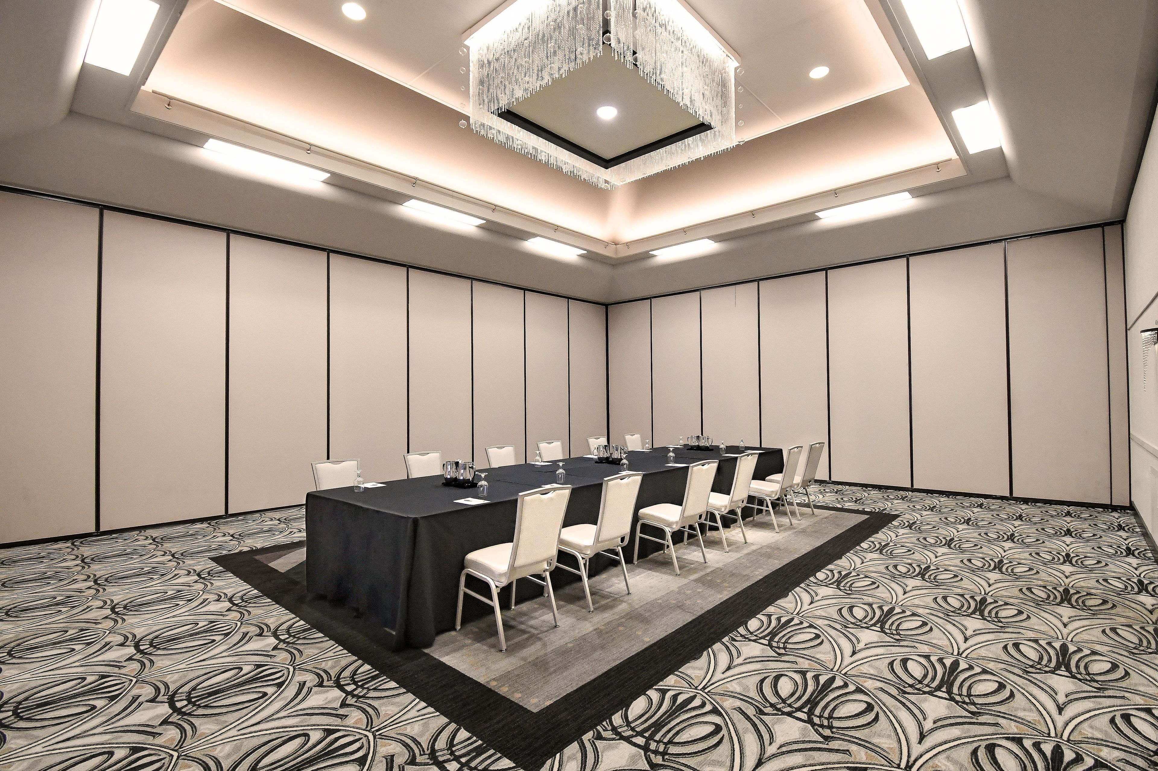 Un salón de conferencias con una larga mesa, sillas y una araña.