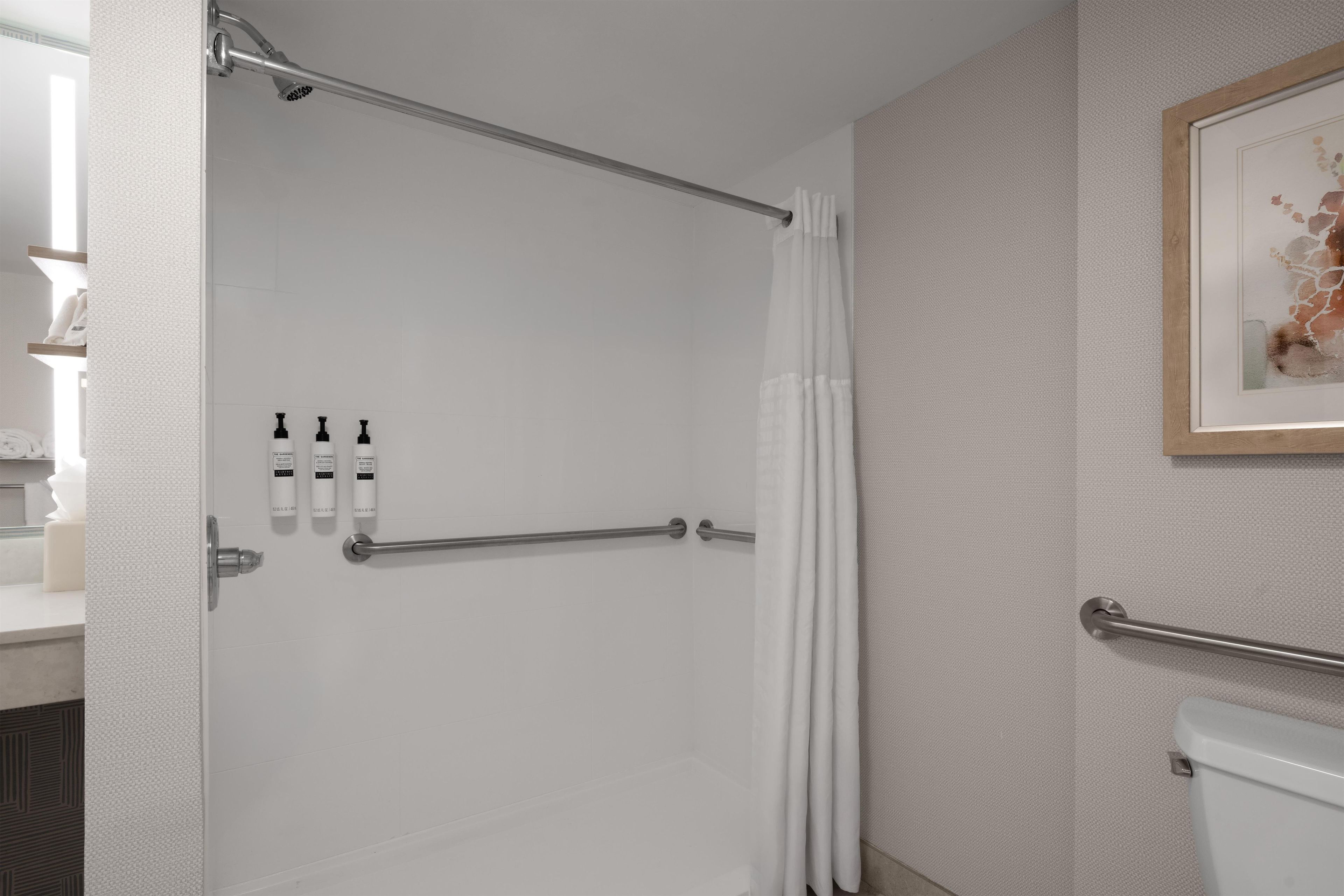 A modern bathroom with a shower, toilet, and hand sanitizer dispensers.
