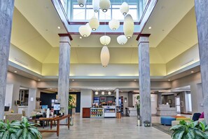 A spacious lobby with a reception desk, seating area, and a food counter. - Hilton Garden Inn Conway (Conway)
