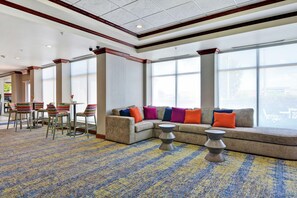 A hotel lobby with a seating area, a coffee table, and a patterned carpet.