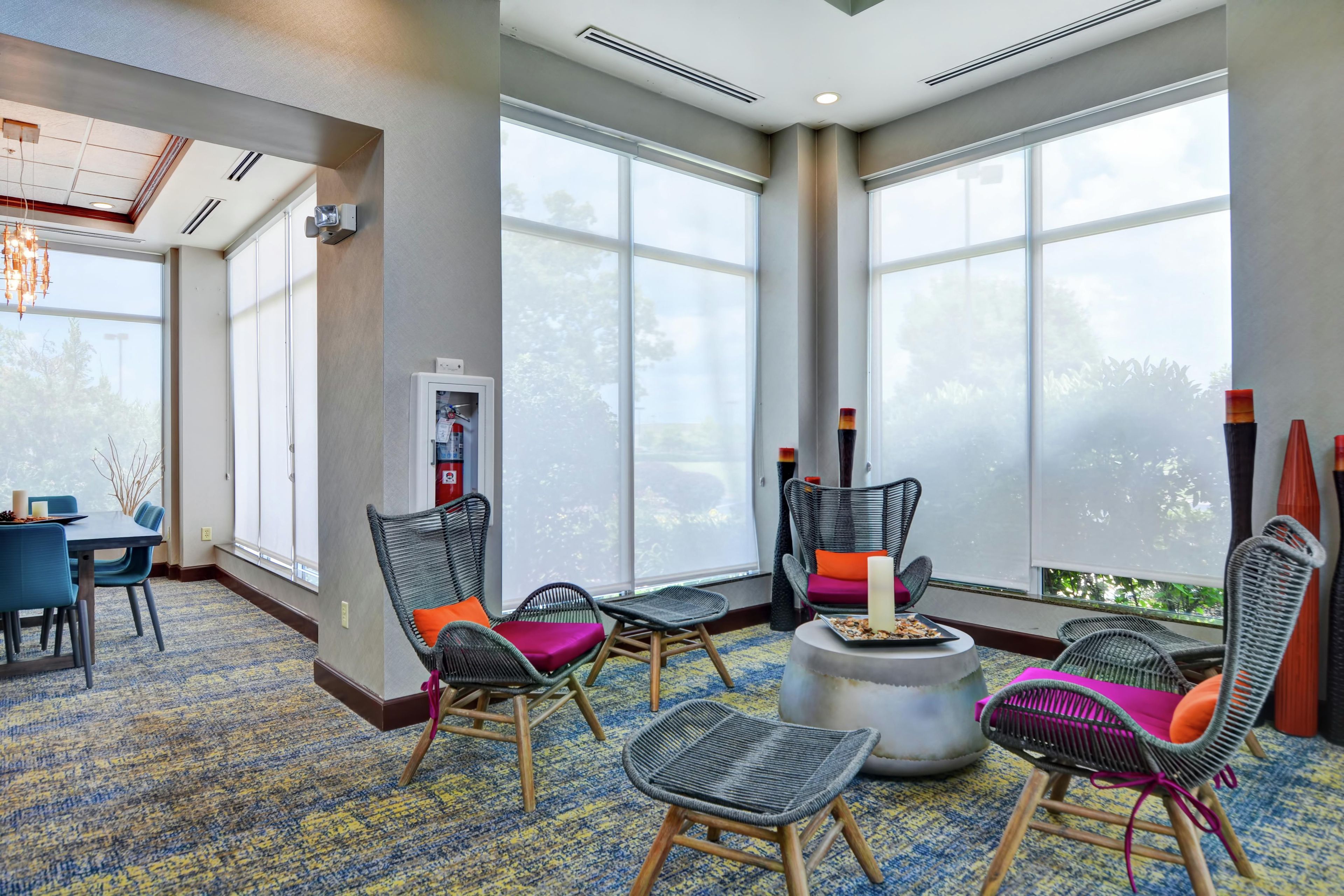 Una habitación amplia con ventanas grandes, muebles de mimbre, una mesa redonda y una chimenea.