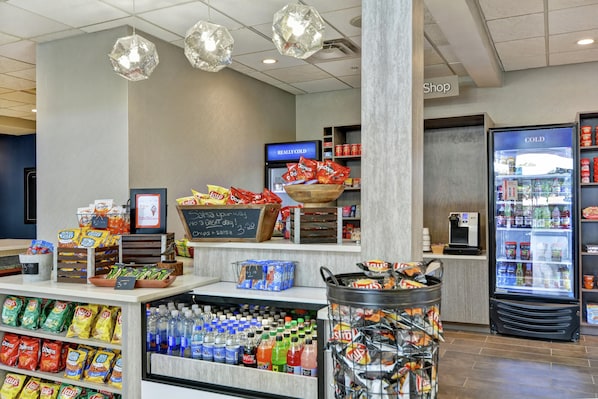 A snack and beverage section in a store with various chips, bottled water, and a cold drink refrigerator.