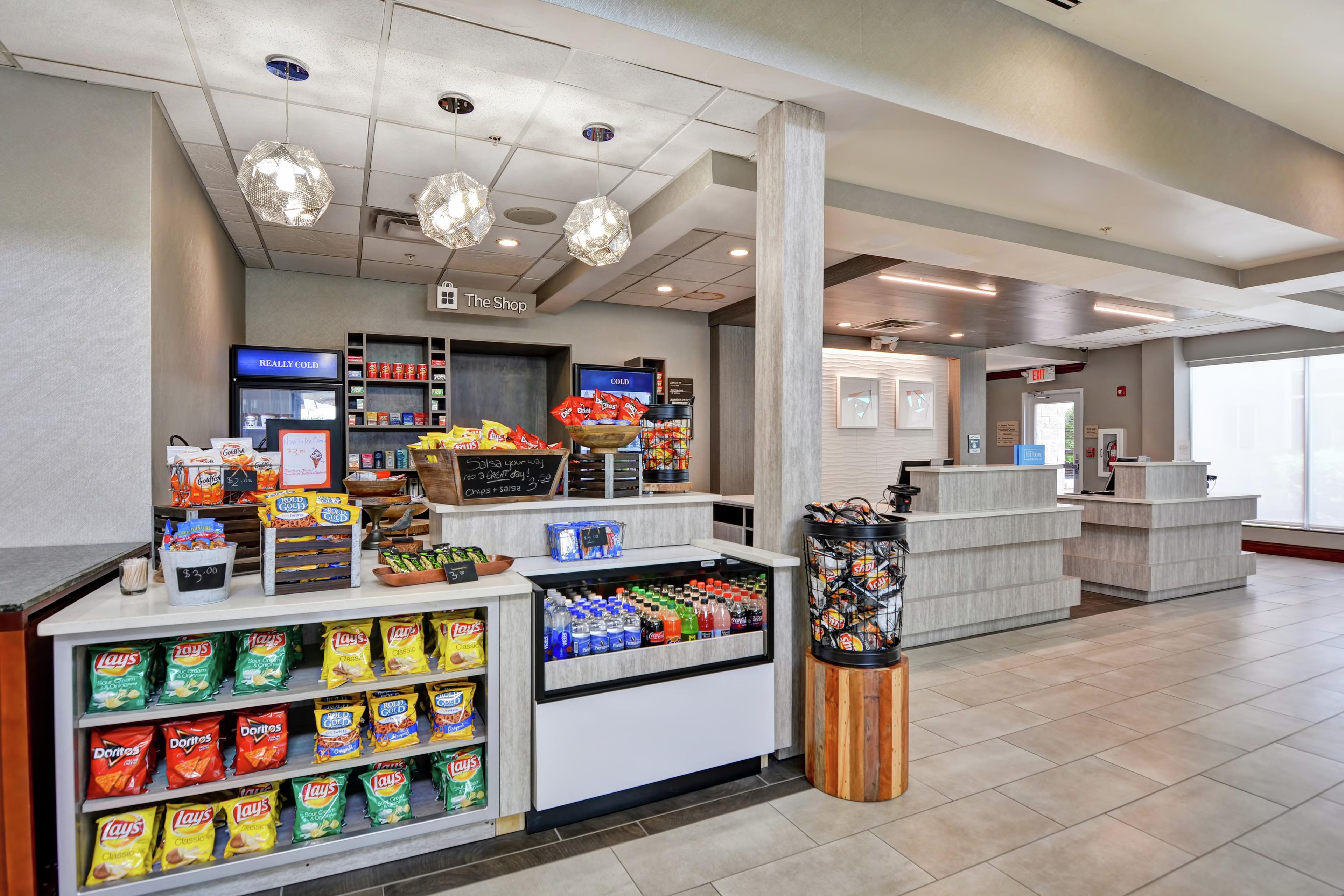 A snack kiosk with chips and salsa, a cash register, and a sign for 'The Shop'.