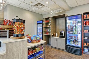 A snack bar area with a variety of snacks, a beverage cooler, and a sign indicating a shop.