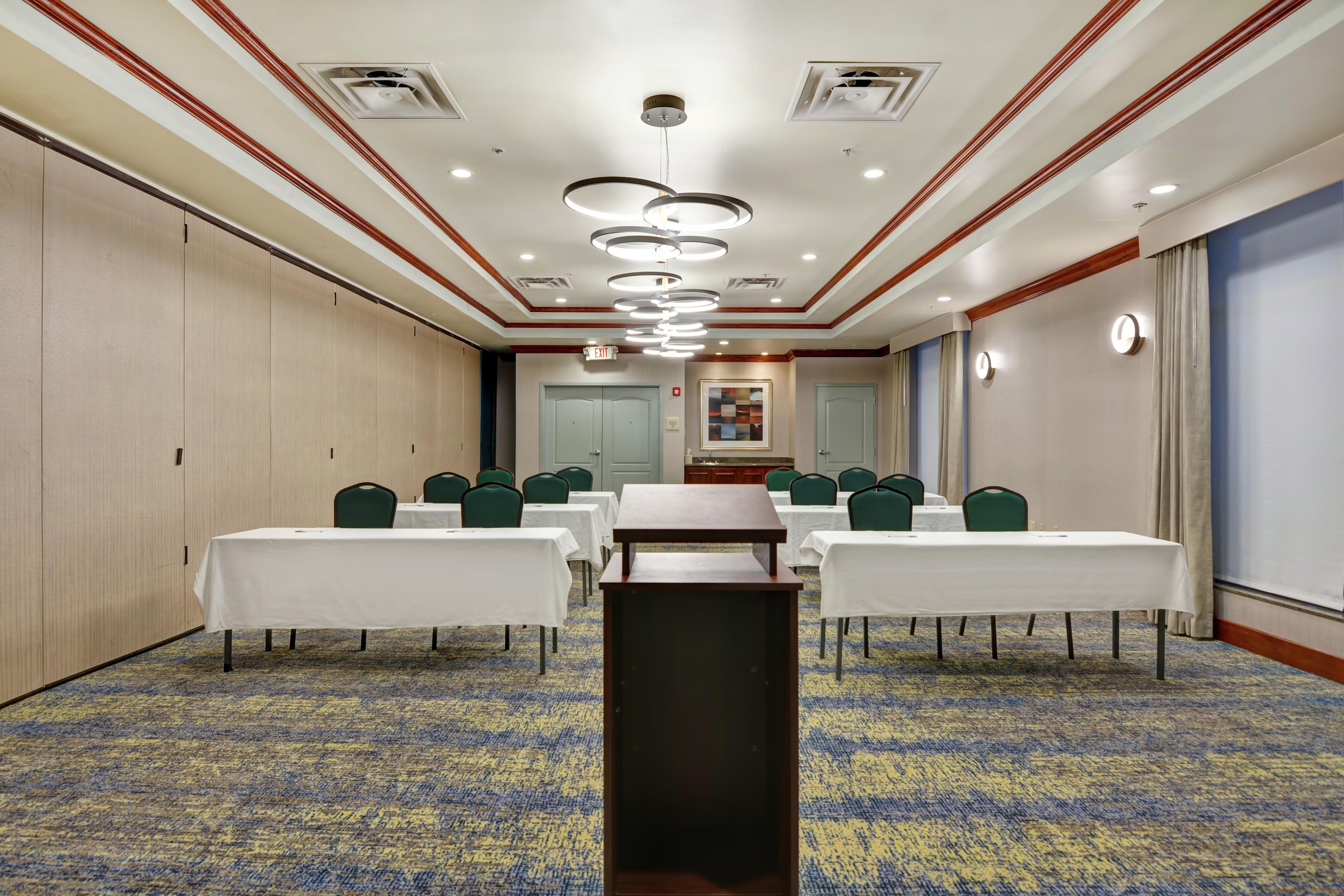 A conference room with tables, chairs, and a carpeted floor.