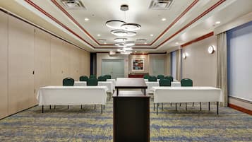 A conference room with tables, chairs, and a carpeted floor.