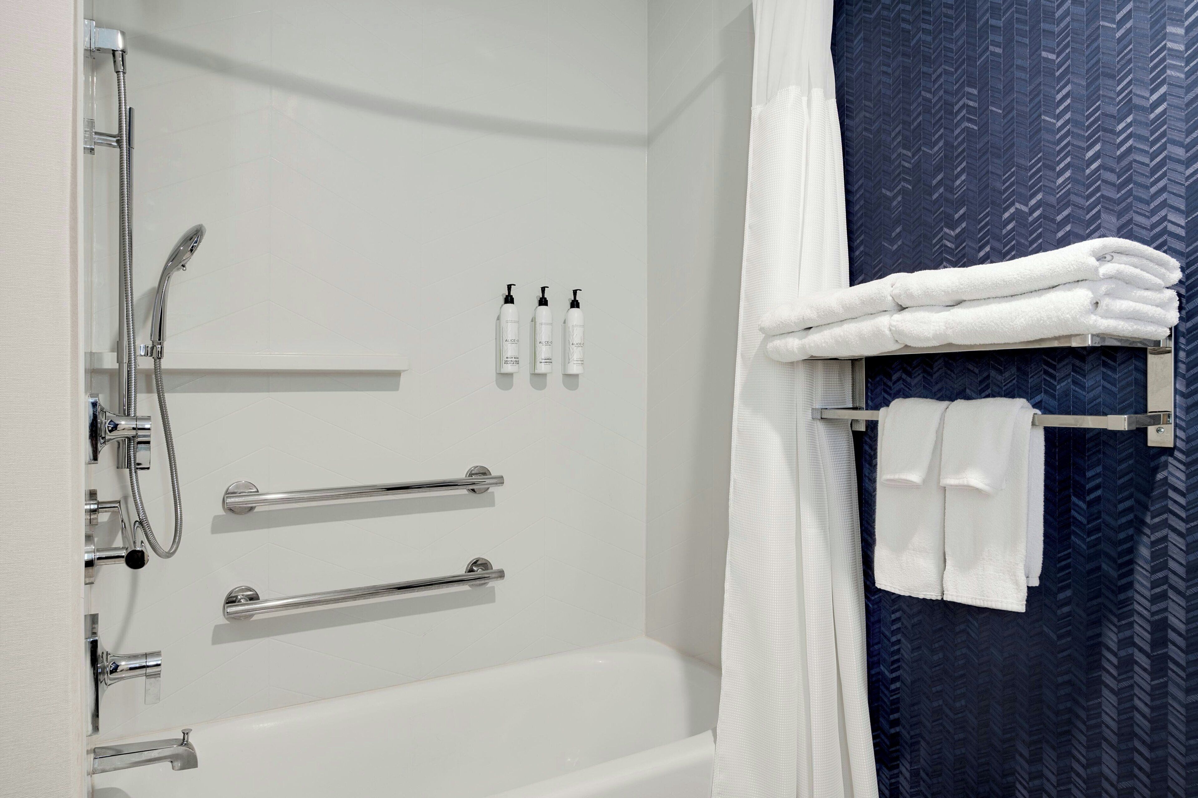A bathroom with a bathtub, a shower, and a towel rack with folded towels.