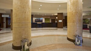 A hotel lobby with large marble columns, a reception desk, and two lit lanterns on the floor. - Hilton Garden Inn Baltimore Inner Harbor (Baltimore)