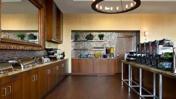A modern kitchen with wooden cabinets, a stone backsplash, and a coffee station with multiple dispensers.