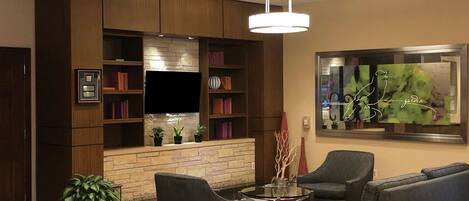 A modern living room with a fireplace, built-in bookshelves, a flat-screen TV, and comfortable seating.