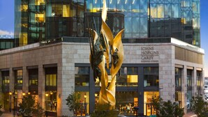 A modern building with a glass facade and a sculpture in front.