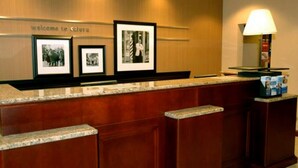 A reception desk with framed photographs on the wall, a welcome sign, and a lamp on the right.
