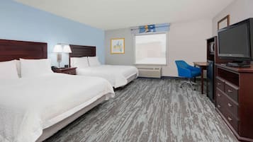 A hotel room with two beds, a desk, a chair, a television, and a window with a view.