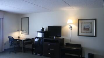 Ein Hotelzimmer mit Schreibtisch, Stuhl, Fernseher und einem gerahmten Bild an der Wand.