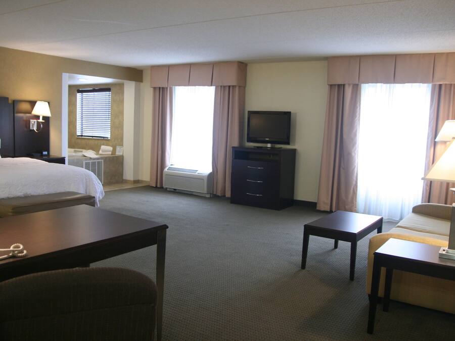 Ein Hotelzimmer mit Bett, Schreibtisch, Fernseher, Stuhl und Lampe.