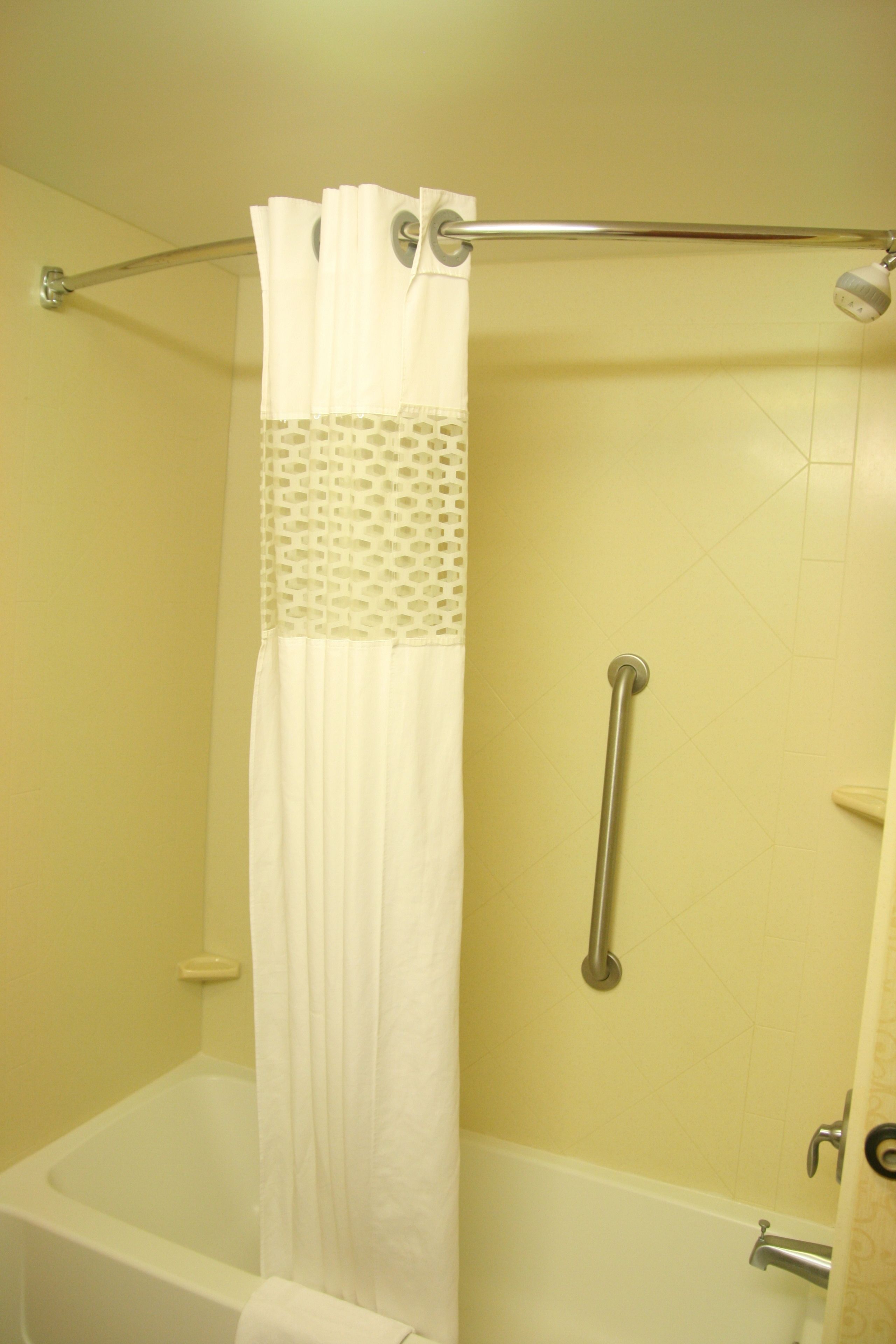 Une salle de bain équipée d’une baignoire, d’un rideau de douche, d’une barre d’appui et d’un porte-serviettes.