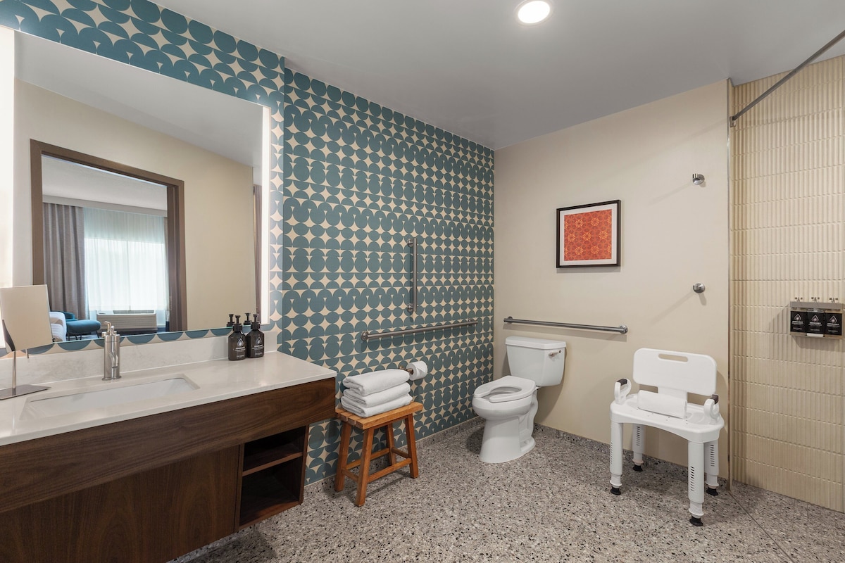 A bathroom with a sink, toilet, and shower chair.