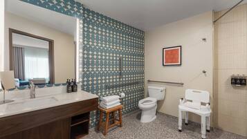 Un baño con lavamanos, inodoro y asiento de ducha.
