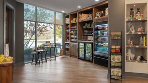 A spacious room with wooden flooring, large windows, and a variety of shelves stocked with snacks and beverages. - Hotel Indigo Columbus Architectural Center by IHG (Columbus)