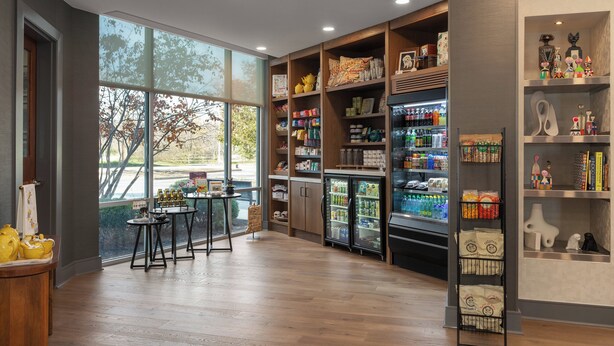 A spacious room with wooden flooring, large windows, and a variety of shelves stocked with snacks and beverages. - Hotel Indigo Columbus Architectural Center by IHG (Columbus)