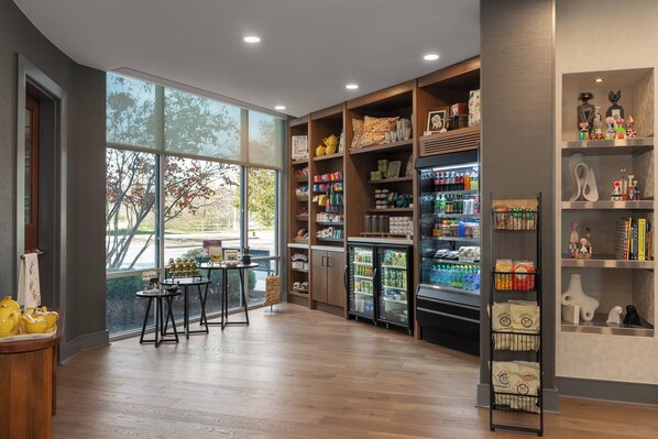 A spacious room with wooden flooring, large windows, and a variety of shelves stocked with snacks and beverages. - Hotel Indigo Columbus Architectural Center by IHG (Columbus)