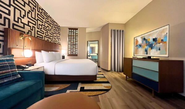 A modern hotel room with a large bed, a desk, a chair, a TV, and a decorative wall panel. - Hotel Indigo Columbus Architectural Center by IHG (Columbus)