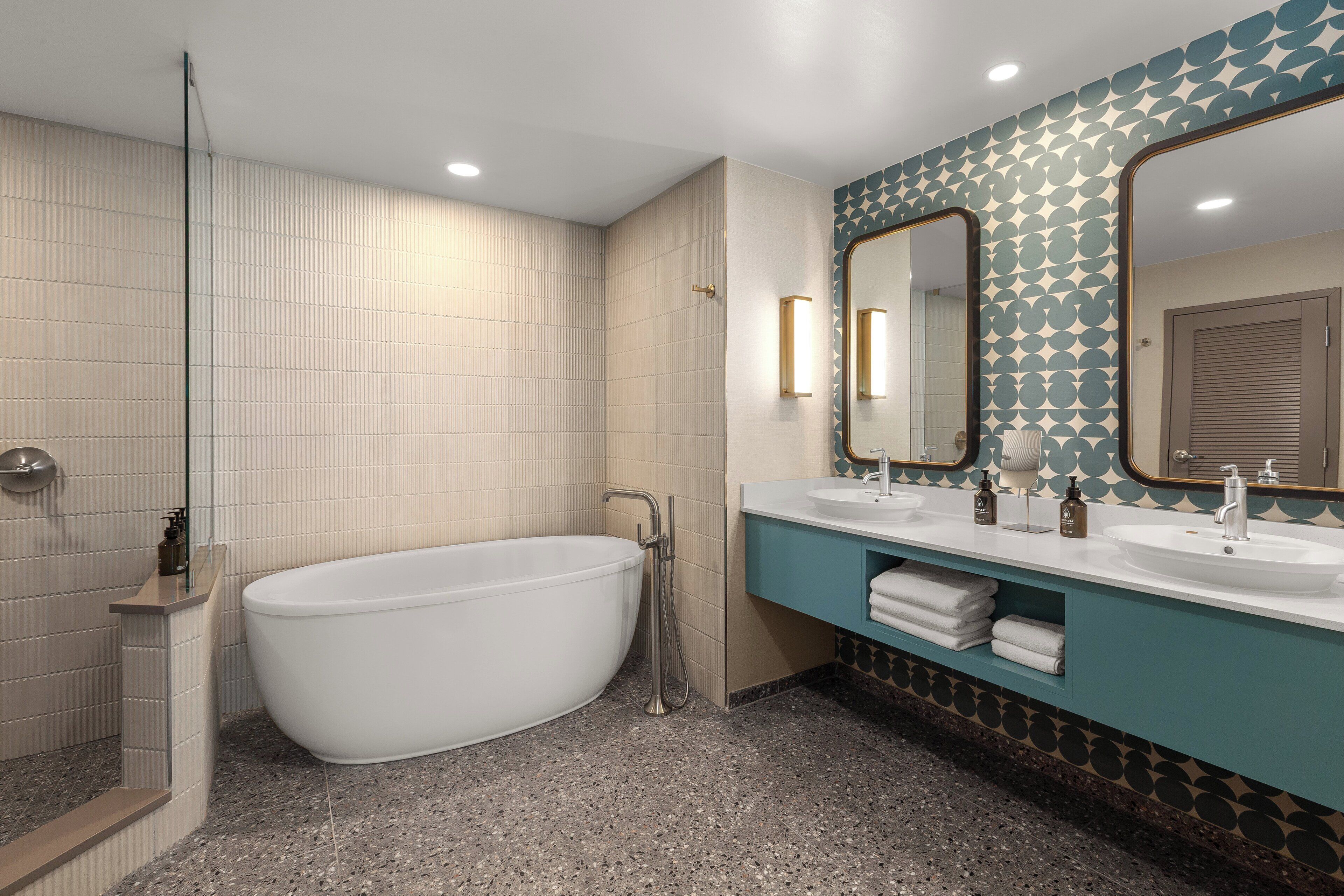 Une salle de bain moderne avec une baignoire sur pieds, deux vasques et un grand miroir.