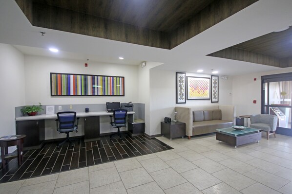 A modern office space with a reception desk, two office chairs, a sofa, and a coffee table. - Holiday Inn Express Hotel & Suites Greensboro - East by IHG (Greensboro)