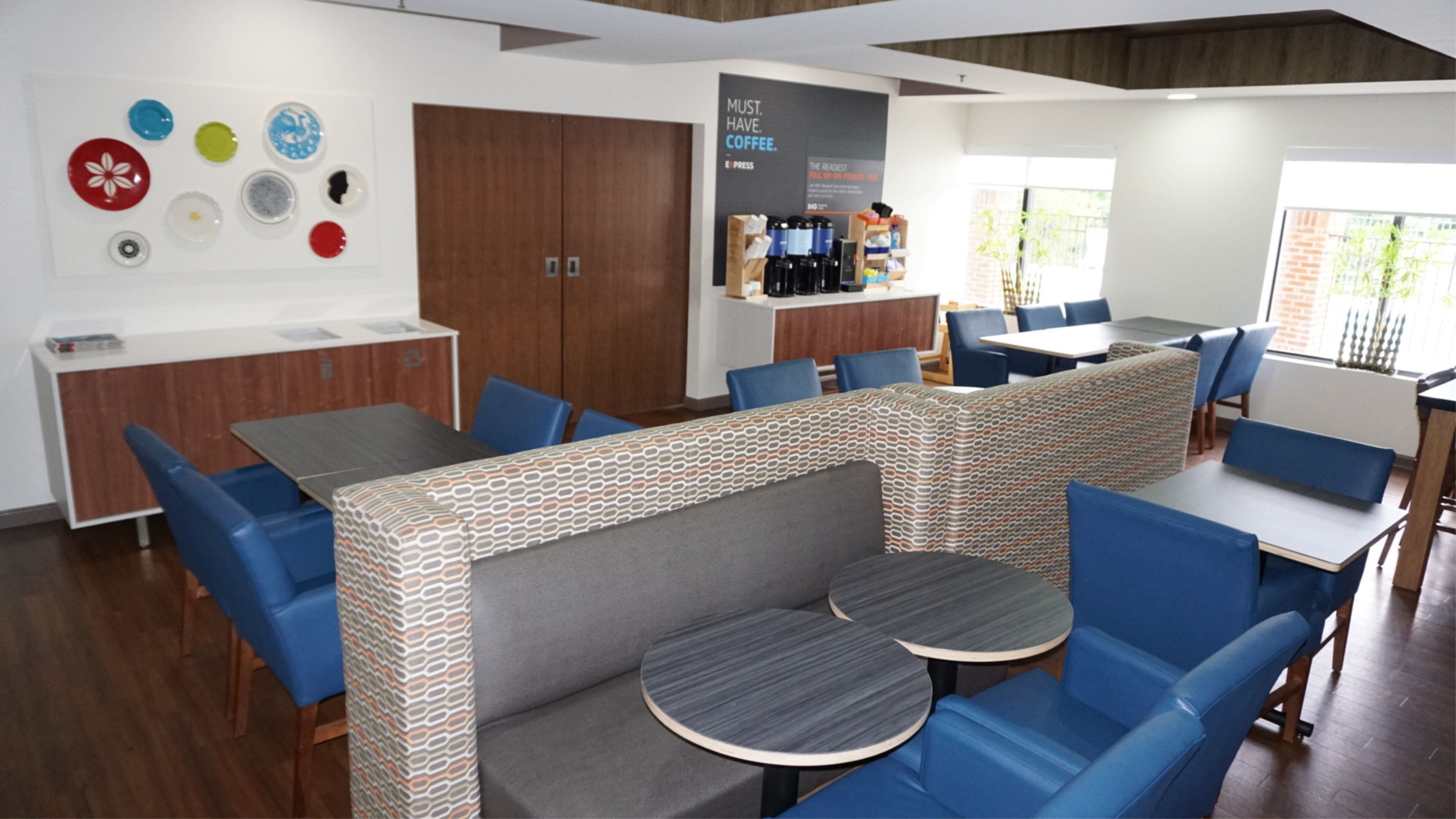 Um café moderno com assentos azuis, um balcão de café e uma parede decorada com pratos.
