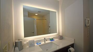 A bathroom with a large mirror, a sink, a toilet, and a telephone.