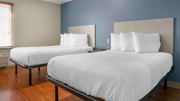 Two twin beds with white bedding in a room with wooden flooring and a blue accent wall.