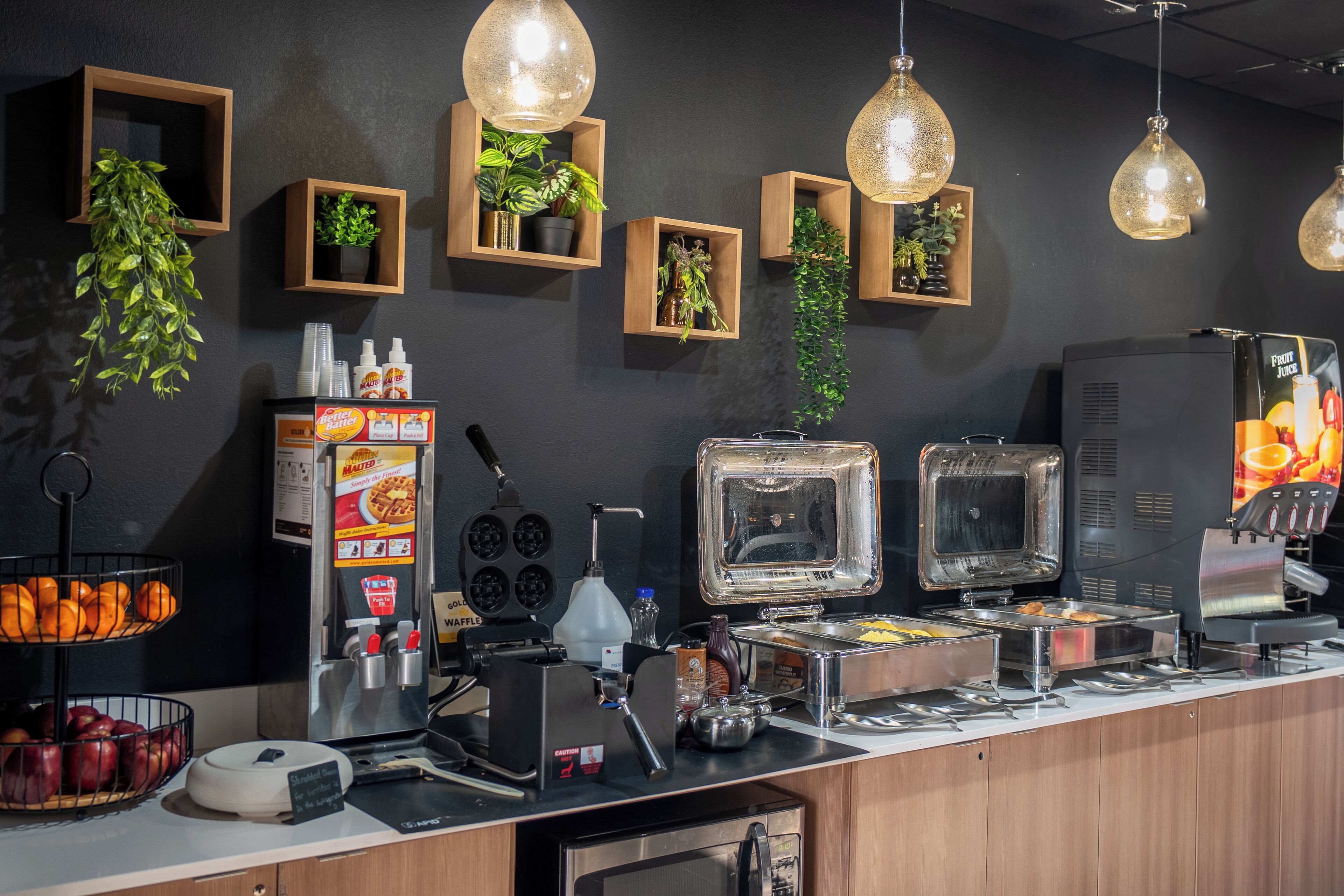 A buffet setup with various food items, a waffle maker, and a coffee machine.