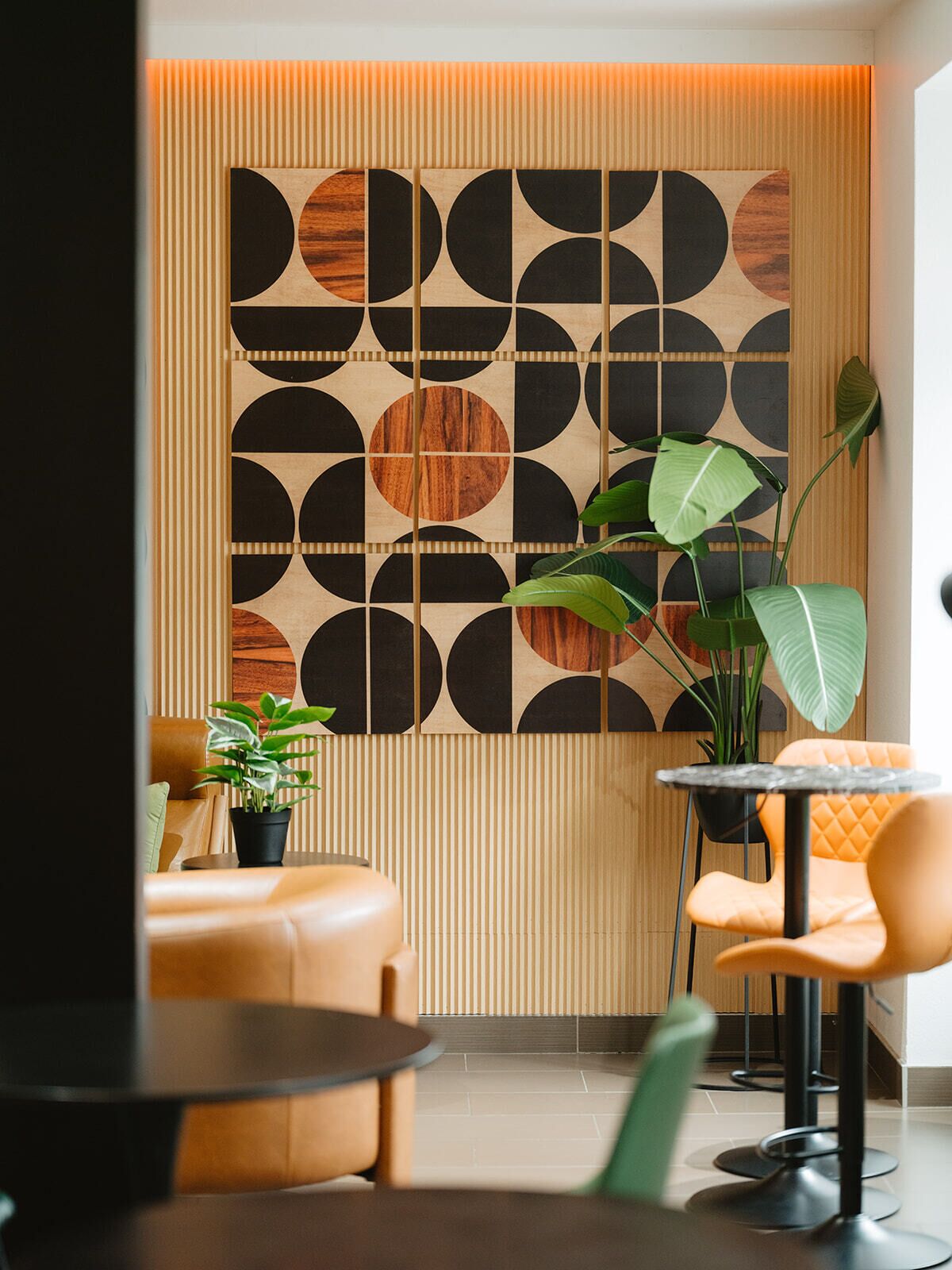 Um interior moderno com parede estampada em padrão geométrico, uma mesa redonda e uma área de estar com uma planta.