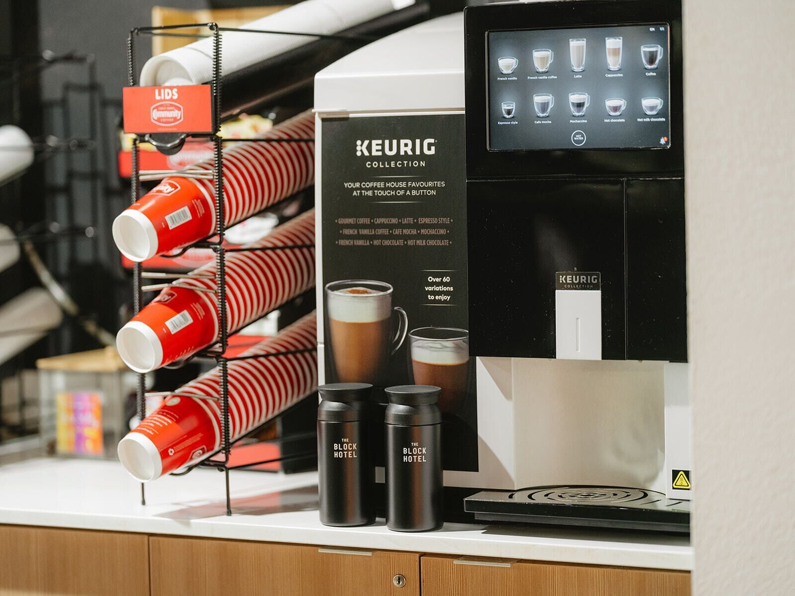 A coffee machine with a touchscreen interface, a coffee cup rack, and branded coffee containers.
