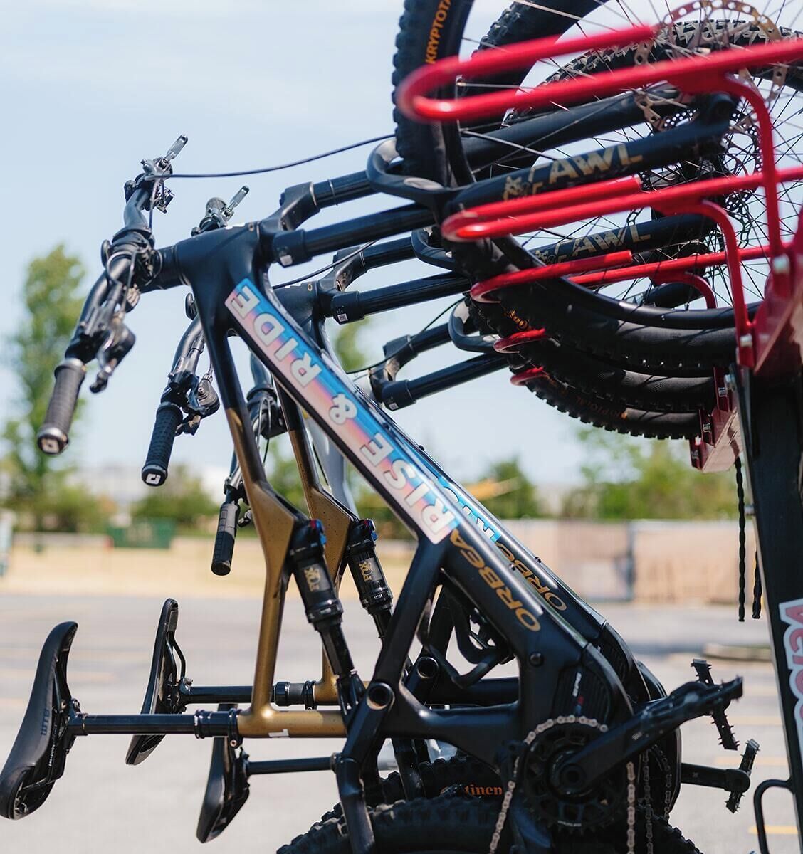 Una bicicleta de montaña con estructura negra y detalles dorados, equipada con múltiples horquillas de suspensión y un portaequipajes trasero.