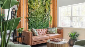 Una sala acogedora con un sofá de cuero, una mesa redonda de centro y una pared cubierta de jardín vertical.