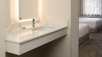 A modern bathroom with a white sink, mirror, and two bedside tables.
