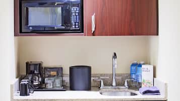 A compact kitchen with a built-in microwave, coffee maker, and refrigerator.
