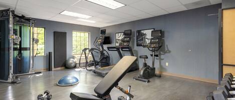 Ein Fitnessstudio mit Trainingsgeräten, Laufbändern und Kurzhanteln.