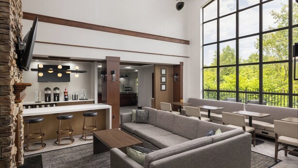 Een moderne lounge met een bank, barstoelen en tafels.