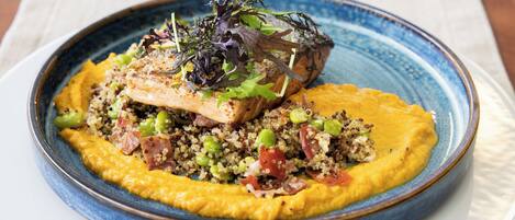 Une assiette de nourriture contenant du quinoa, des légumes verts et un morceau de viande, le tout servi dans une assiette bleue.
