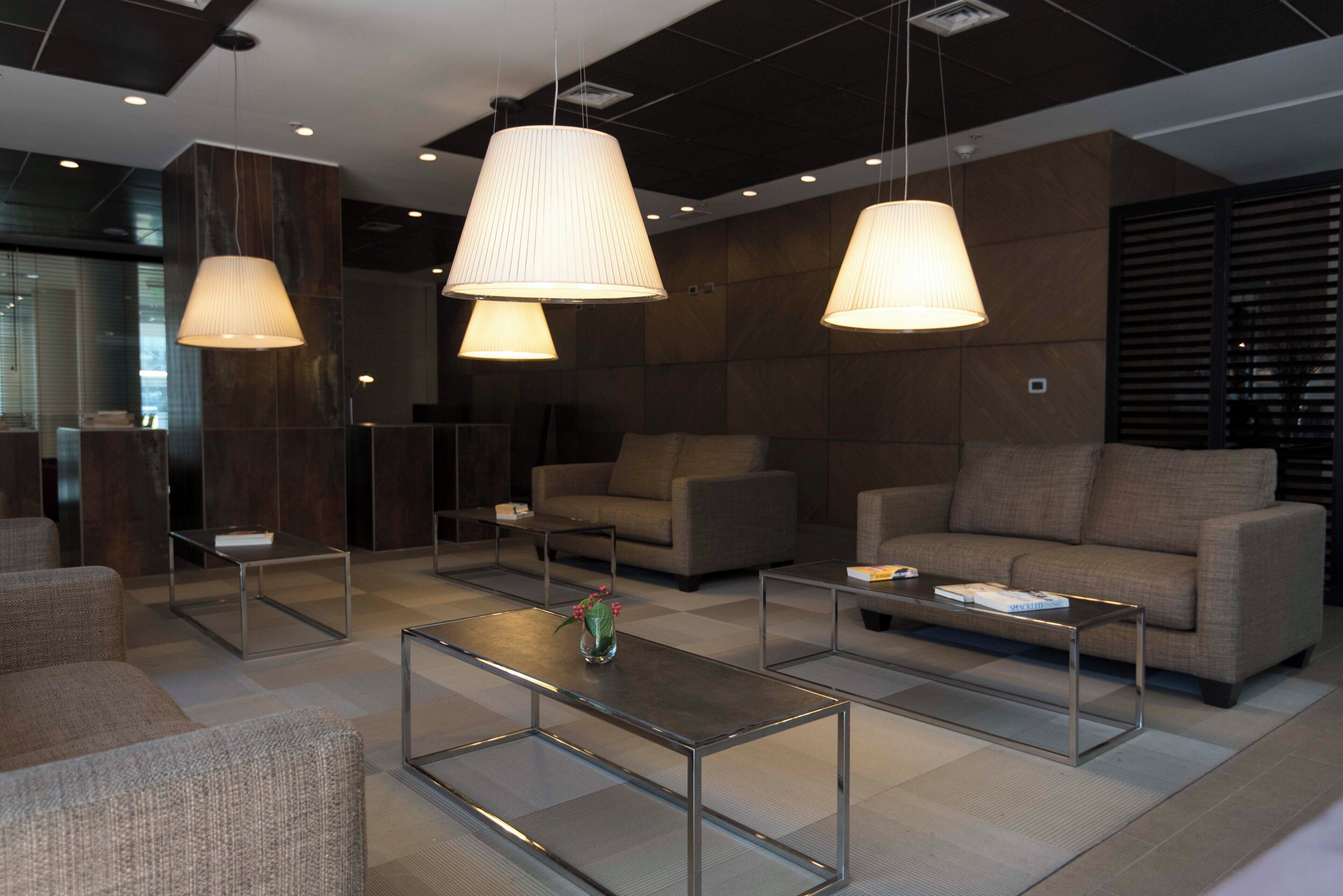A modern lounge area with sofas, coffee tables, and pendant lighting.