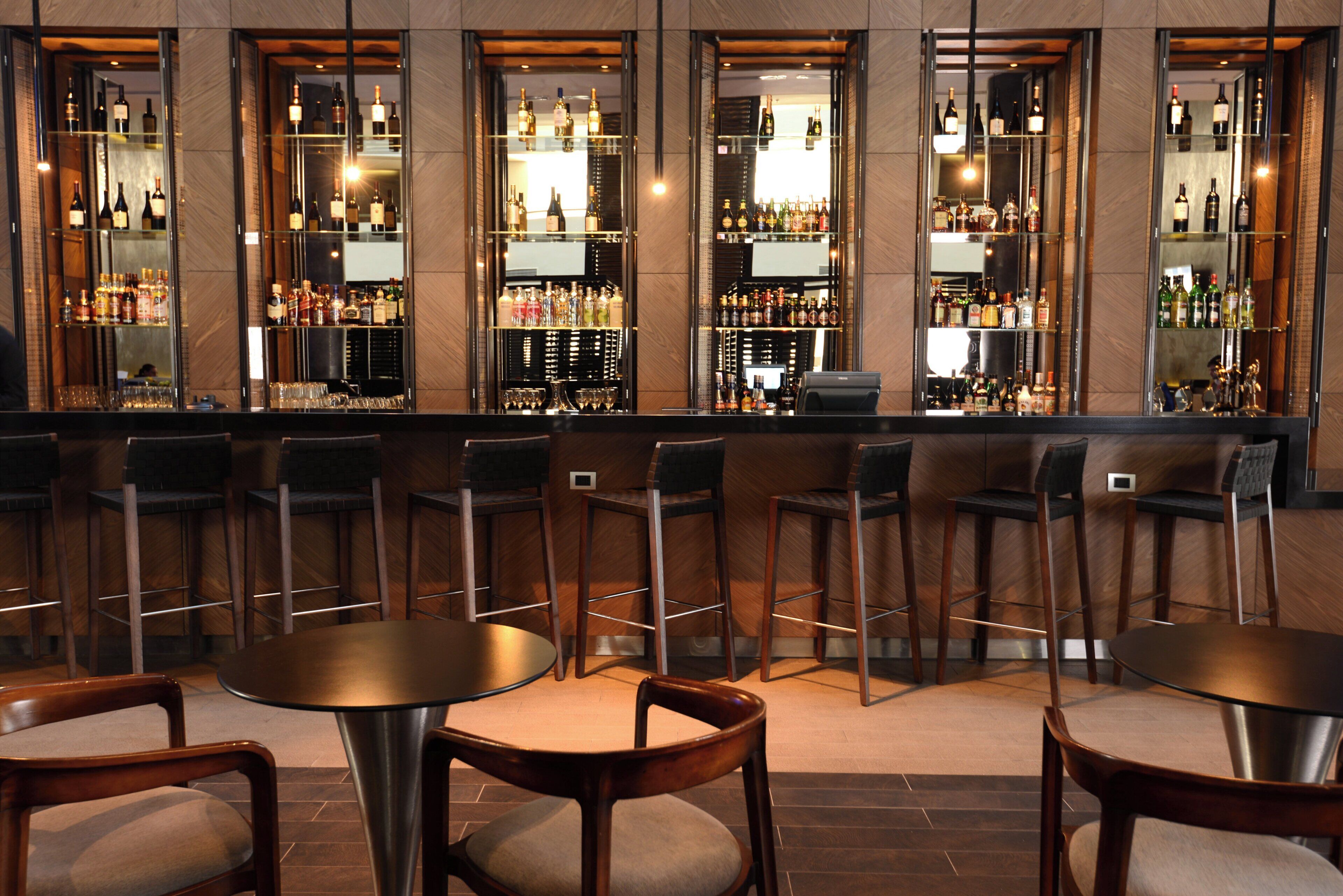 Un espace bar offrant différentes options de sièges, notamment des tabourets de bar et des tables rondes.