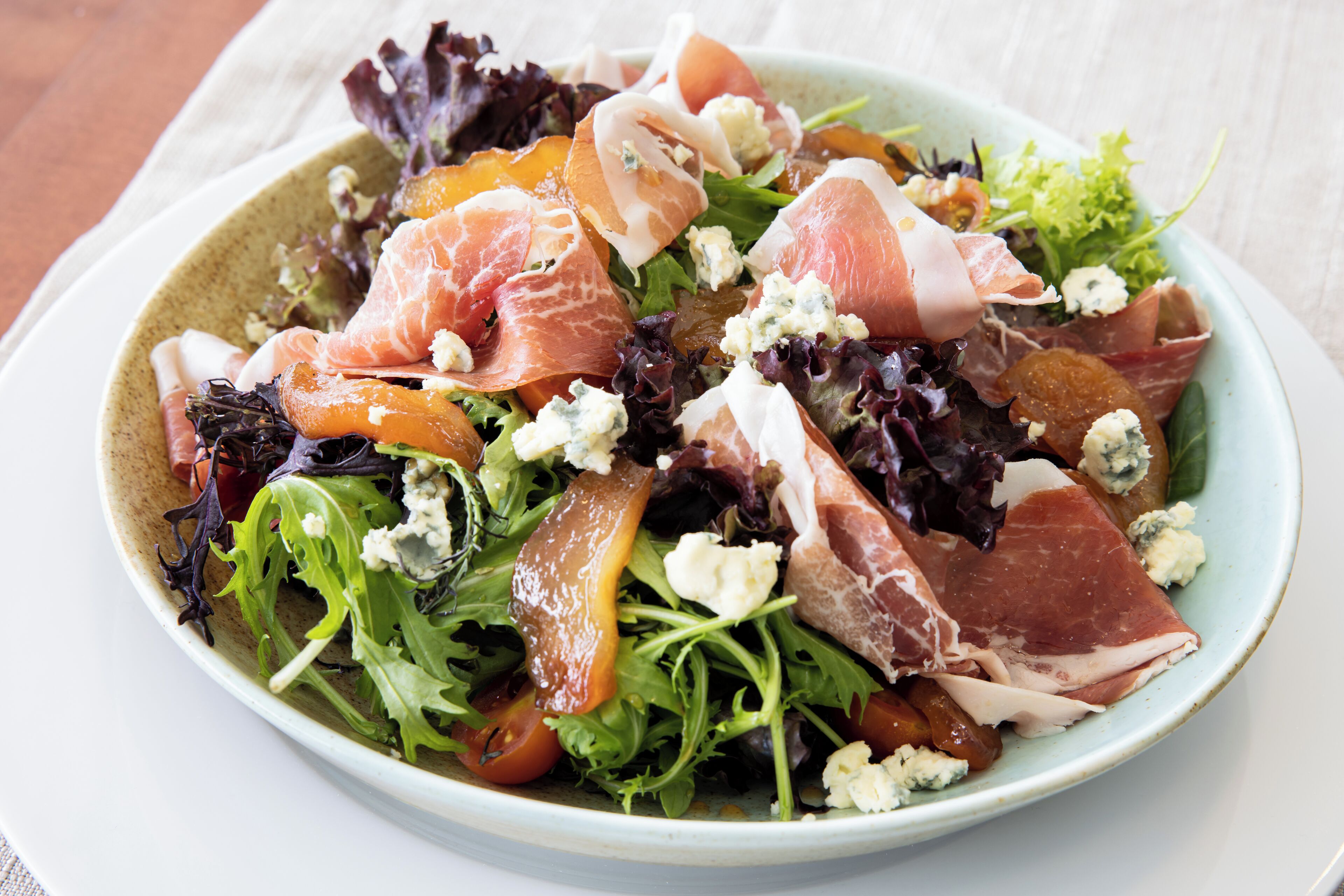 A salad with various greens, tomatoes, and cheese.