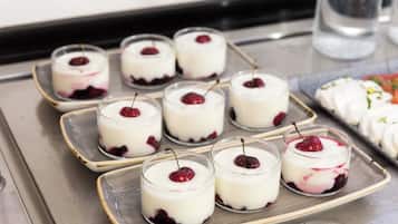 Una bandeja con copas de postre y cerezas sobre una superficie metálica.