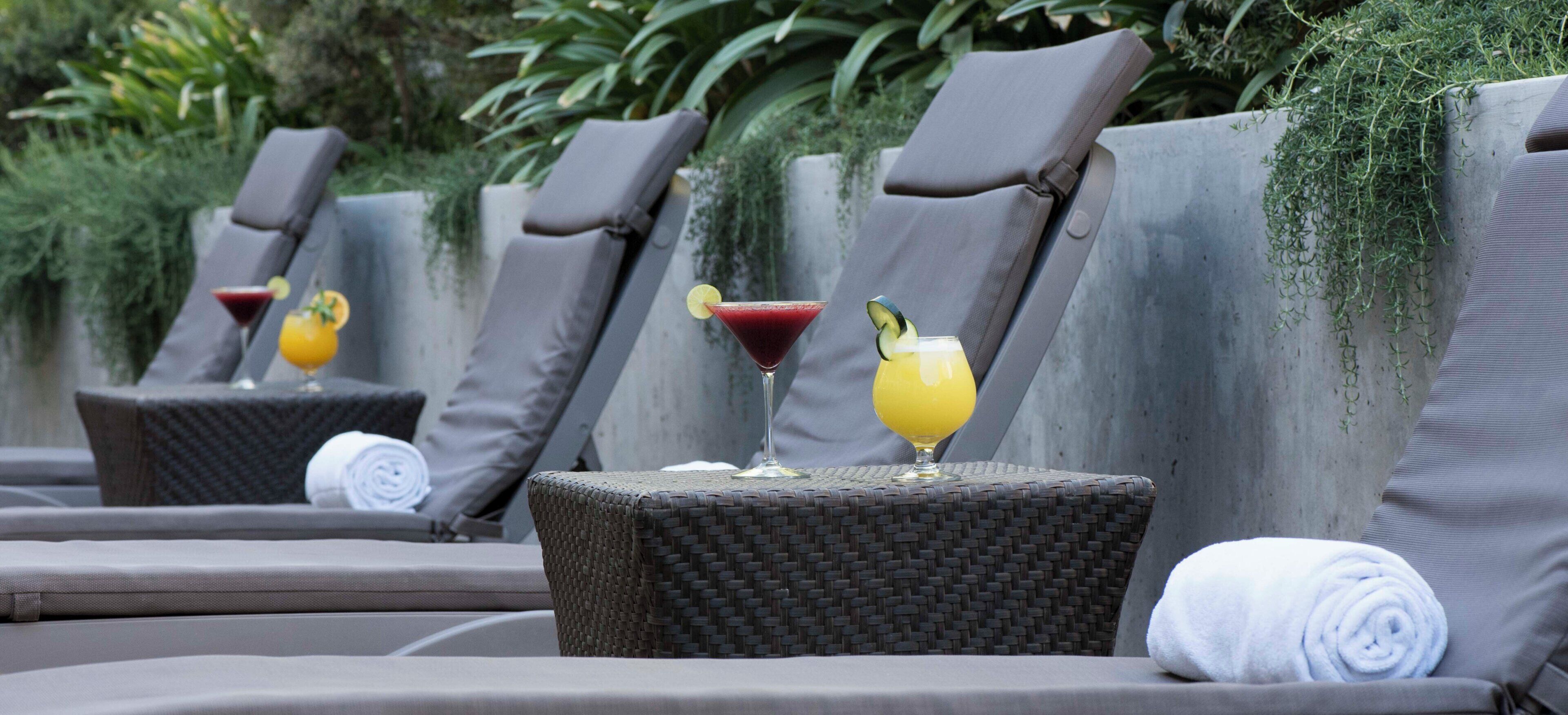 A row of lounge chairs with drinks and towels, suggesting a relaxation area.