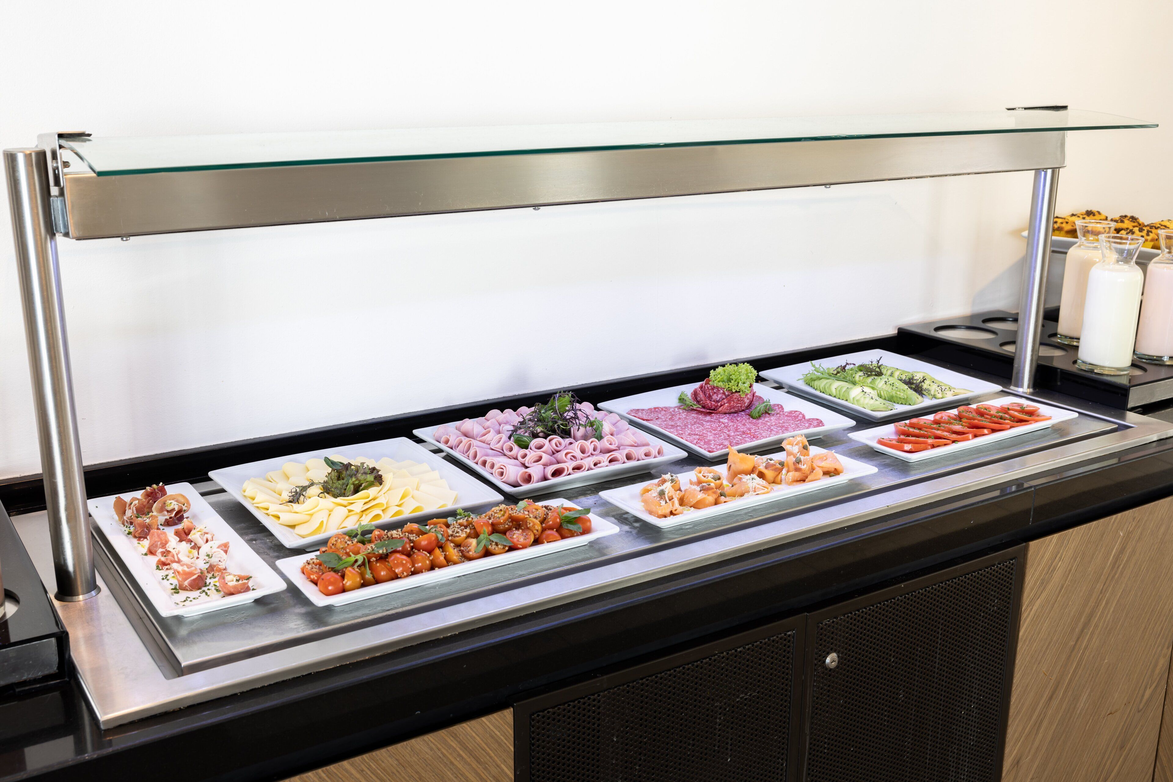 A buffet with various food items including salads, meats, and cheeses.