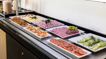 A buffet with various food items including meats, cheeses, and vegetables.