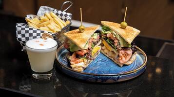 A sandwich cut in half with a toothpick, a basket of fries, and a glass of milk on a table.